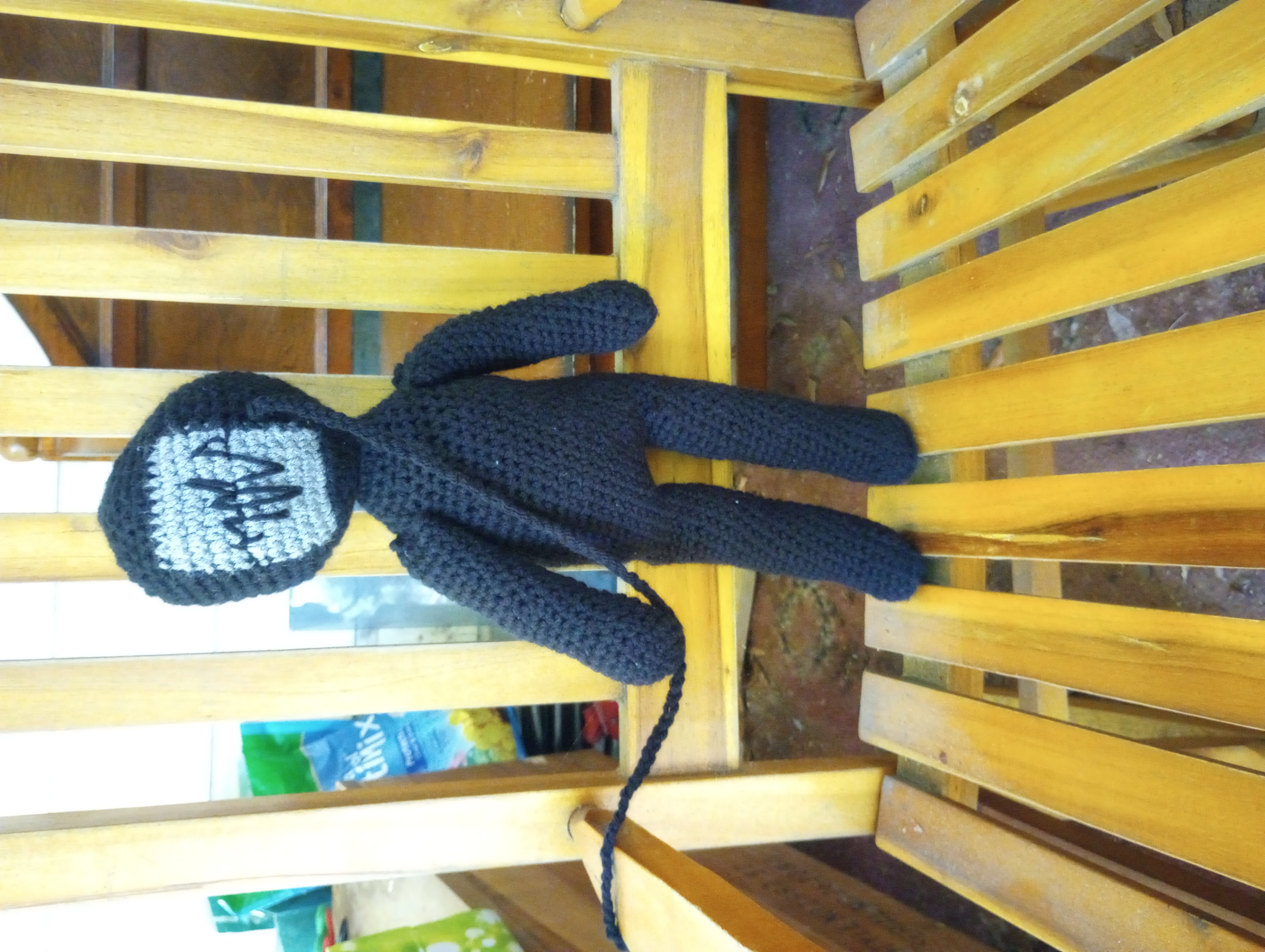 A close-up of the crocheted doll, with the cord for the headphones stretching out of the frame