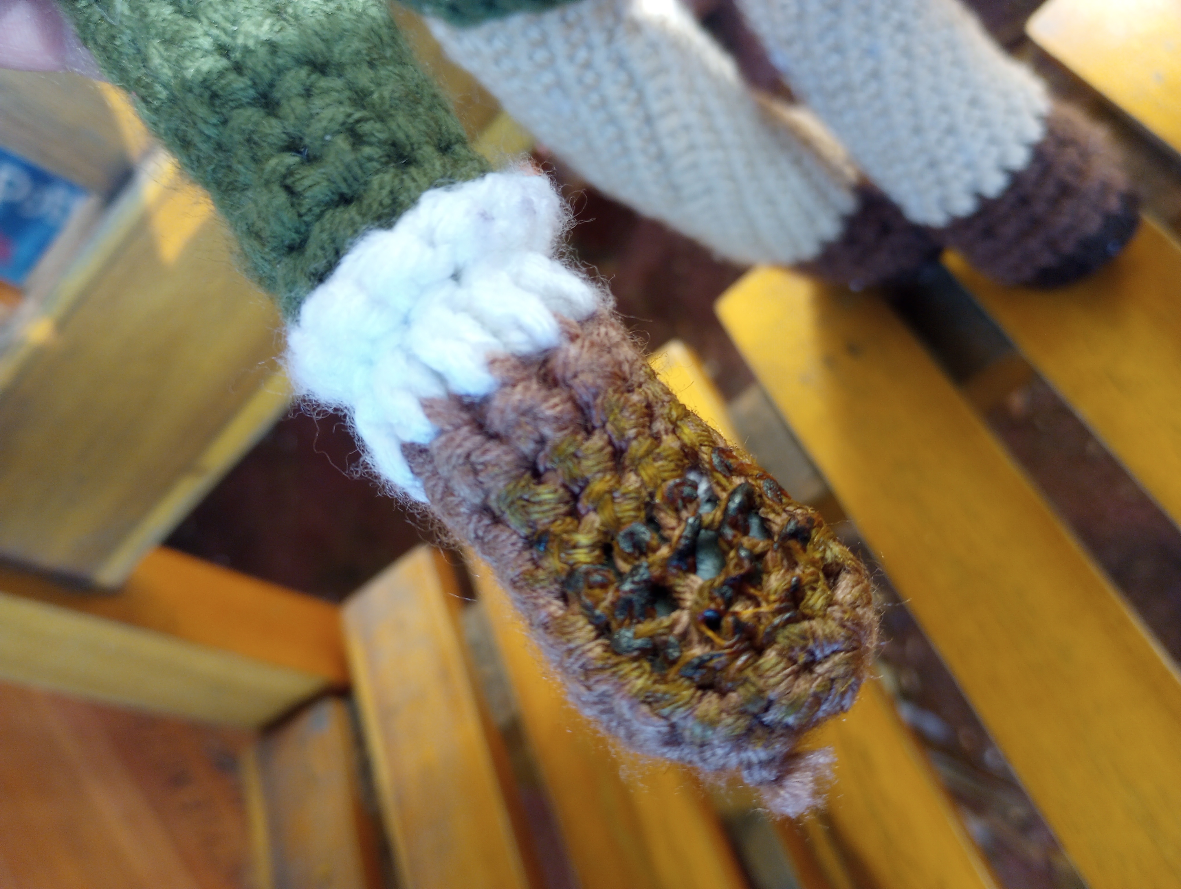 A close-up of the doll's right hand. The middle of it is blackened and twisted, and the yarn around it has discolored to a sickly yellowish-tan. The magnet in the center is visible through the gaps in the yarn