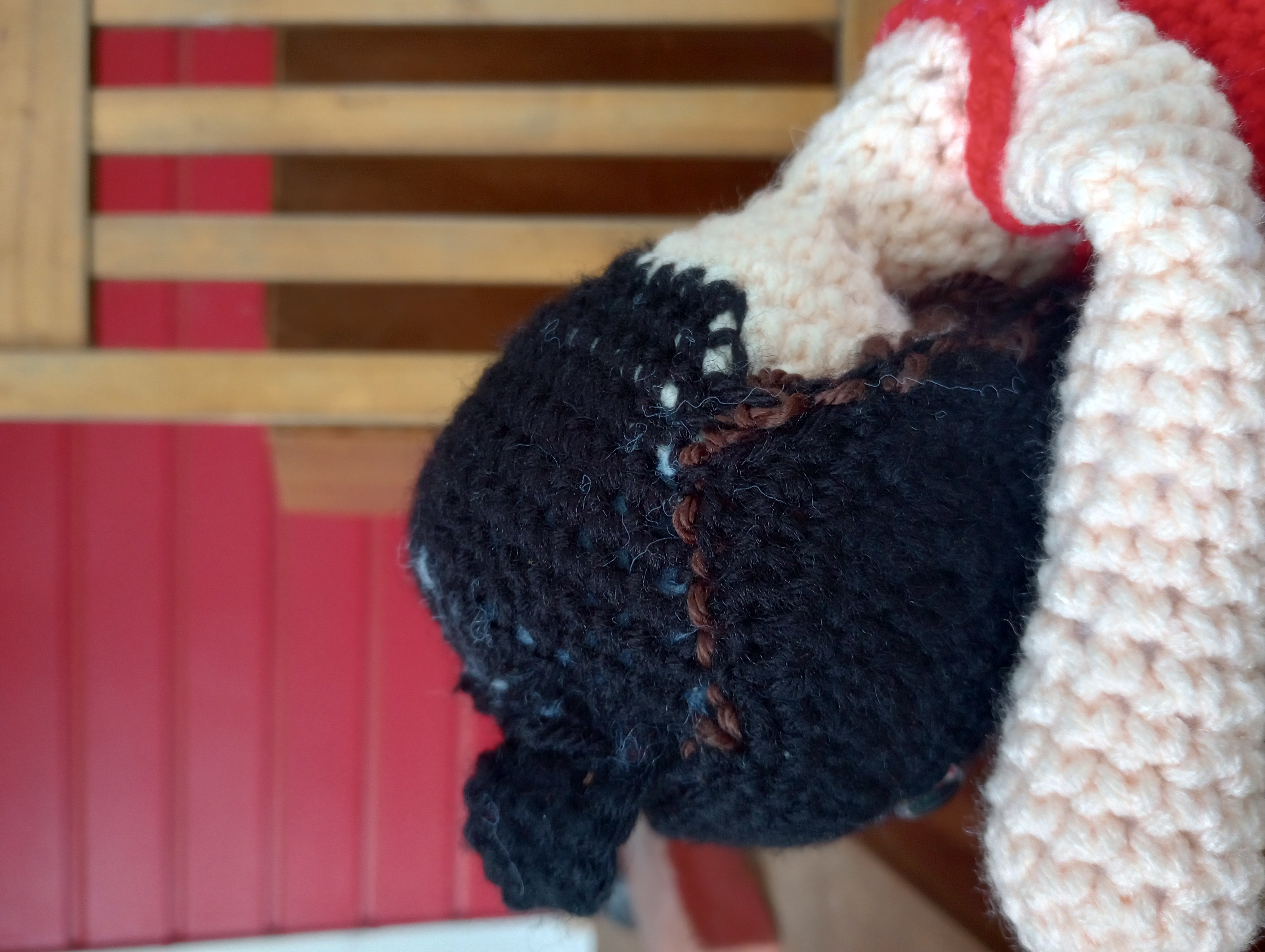 The same doll close up from the side, the head leaning against the arm of the chair, showing the stitching along the hairline